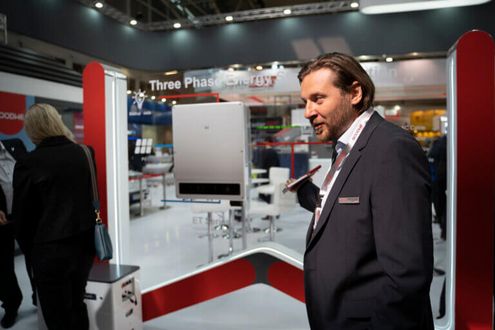 Zástupce firmy GoodWe Eugen Budjugin s hybridním střídačem v pozadí.